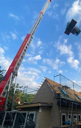 mobiler Kran hebt Arbeitsmaterialien auf ein Dach